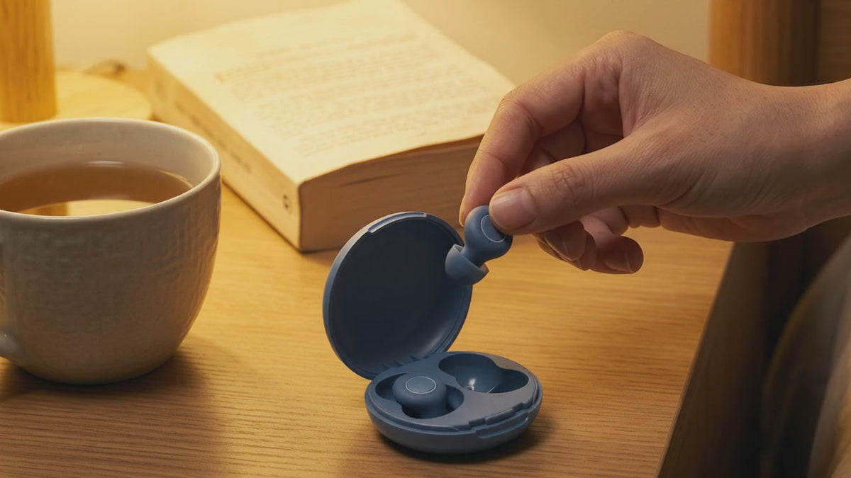 Main qui prend un bouchon d'oreille Quiet Sommeil dans son étui sur la table de nuit