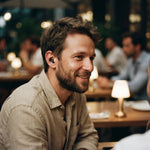Homme au restaurant portant un bouchon d'oreille Quiet Social noir, discret dans l'oreille