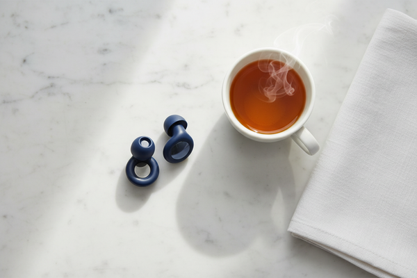 Bouchons d'oreilles Quiet Sommeil bleus sur du marbre, à côté d'une tasse de thé