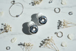 Bouchons d'oreilles QUIET Adapte argentés avec embouts en silicone blanc sur un fond en marbre élégant