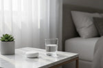 Étui de rangement rond blanc QUIET pour bouchons d'oreilles posé sur une table en marbre près d'un verre d'eau