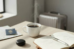 Étui de rangement noir QUIET pour bouchons d'oreilles posé sur un bureau près d'une tasse de café et d'un carnet.