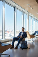 Homme assis dans un salon d'aéroport portant des bouchons d'oreilles QUIET Quiet Adapte pour une réduction du bruit