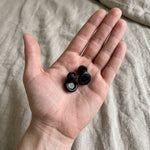 Deux bouchons d'oreilles Quiet Sommeil noirs dans le creux de la main, pour montrer leur petite taille