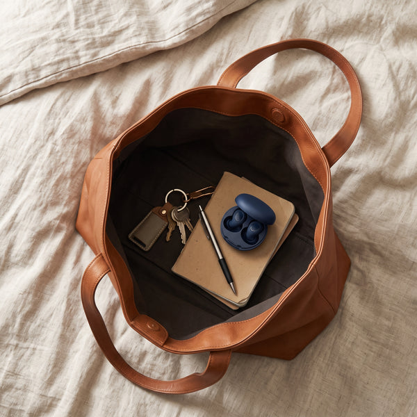 Étui Quiet Sommeil bleu glissé dans un sac en cuir, avec des clés et un carnet