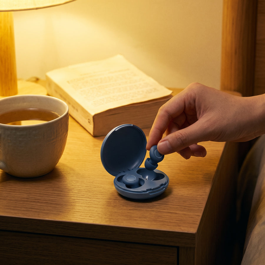 Main qui prend un bouchon d'oreille Quiet Sommeil bleu dans son étui, sur la table de nuit